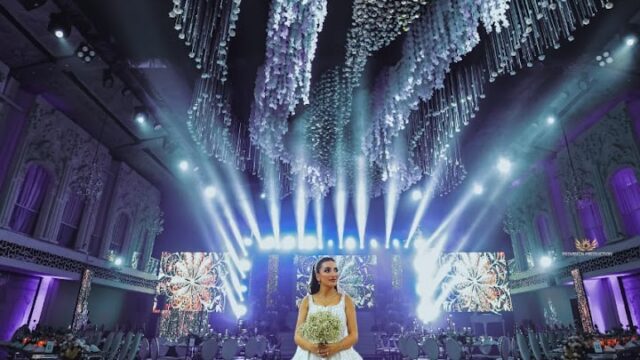 a woman in a white dress holding a bouquet in a room with lights