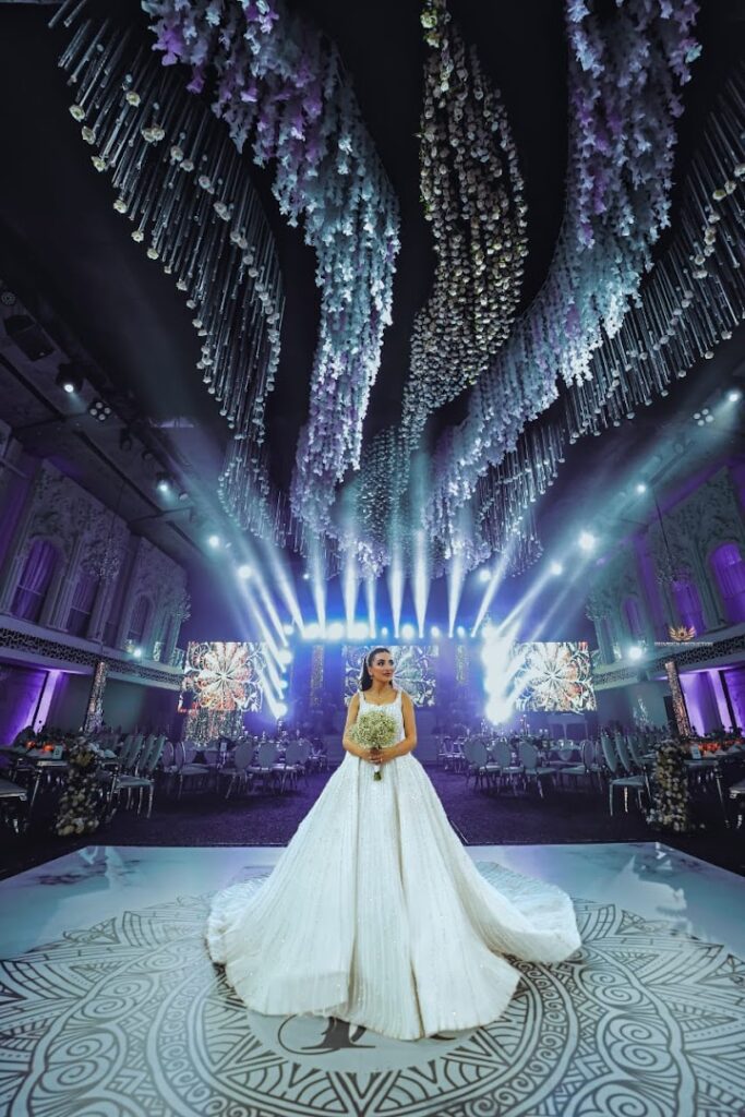 a woman in a white dress holding a bouquet in a room with lights