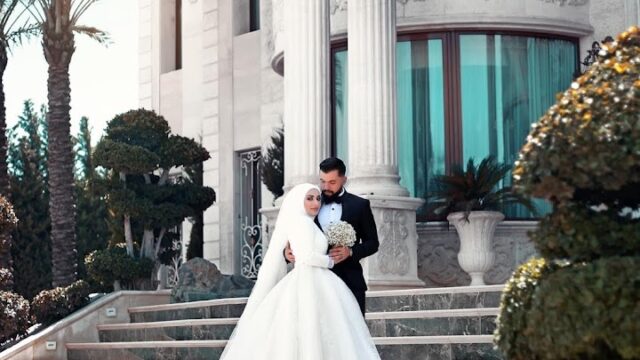 a man and woman in wedding attire standing on stairs in front of a building