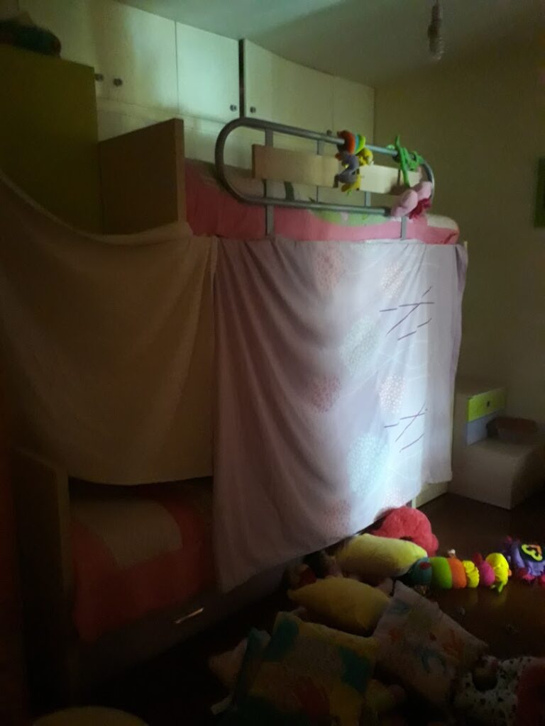 a bed with a blanket and toys on the floor