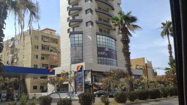 a building with palm trees and a parking lot