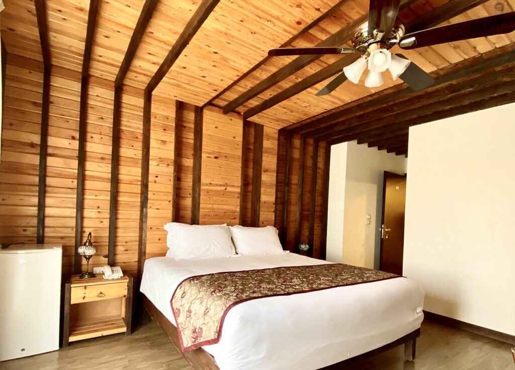 a bed in a room with wood walls and ceiling fan