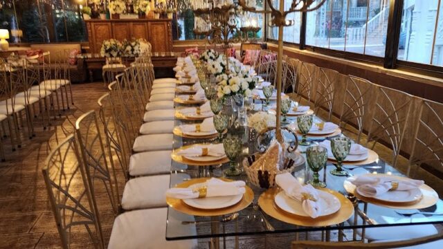 a long table set with white chairs and candles