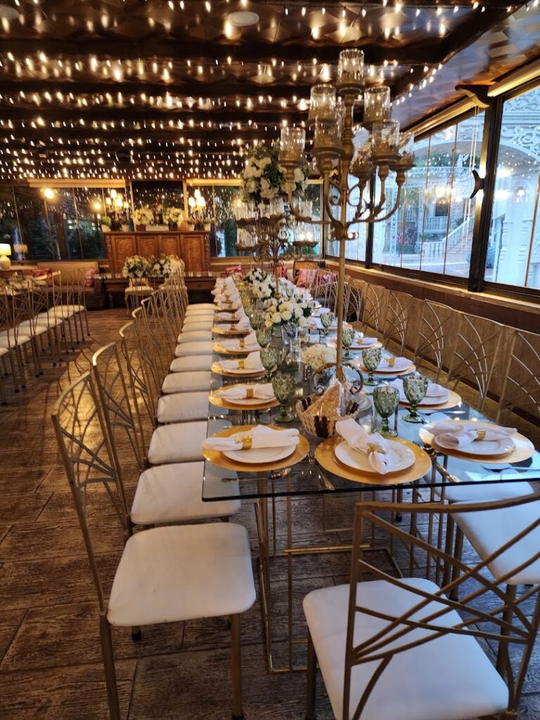 a long table set with white chairs and candles