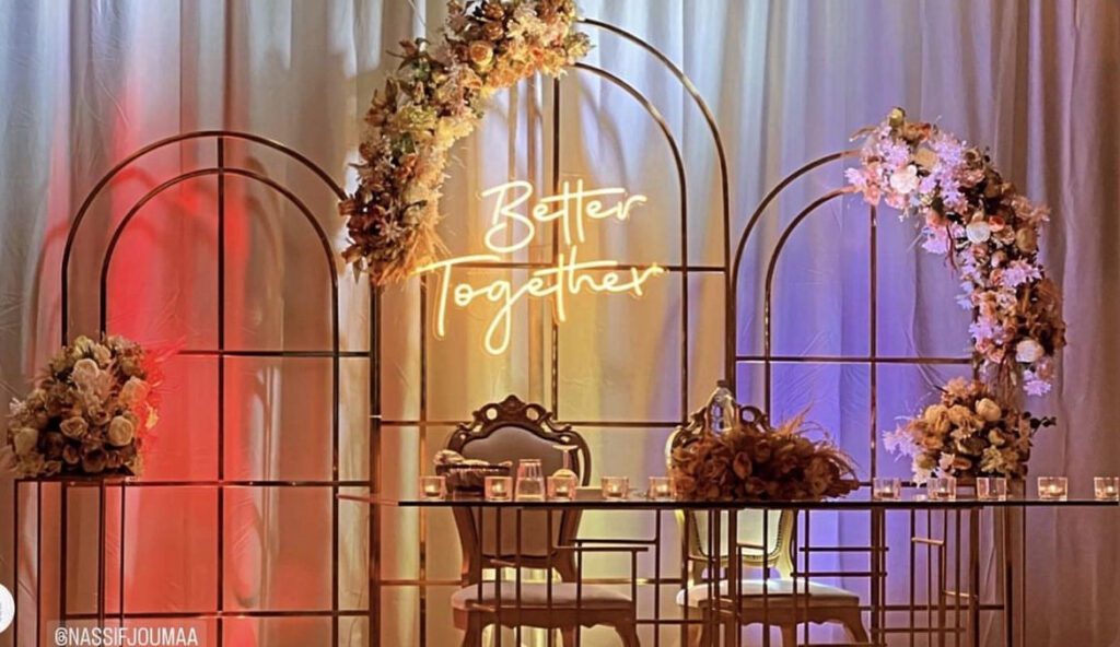 a table with chairs and flowers under a arch