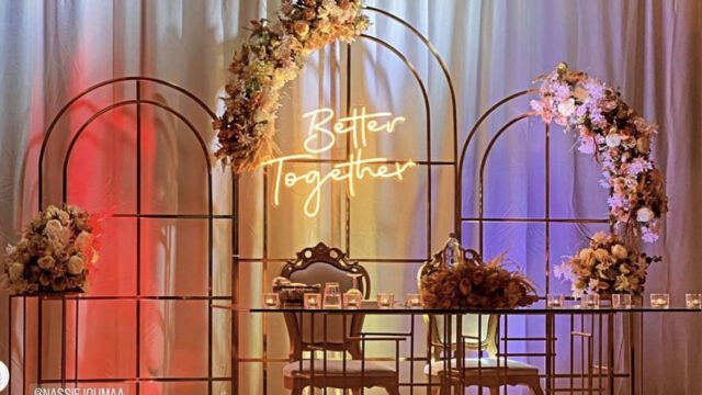 a table with chairs and flowers under a arch