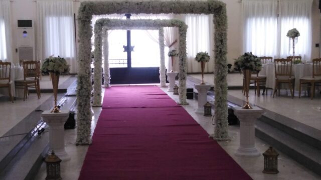 a wedding ceremony with a red carpet and white flowers