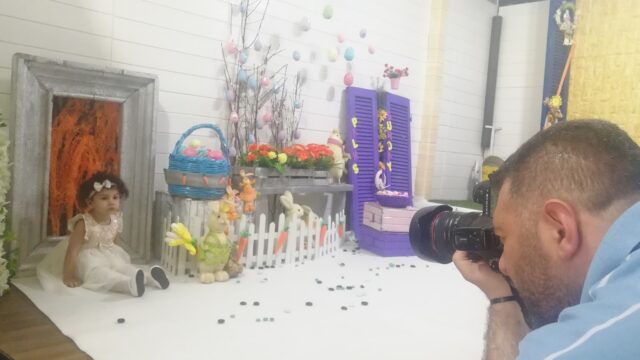 a man taking a picture of a girl sitting on a white carpet