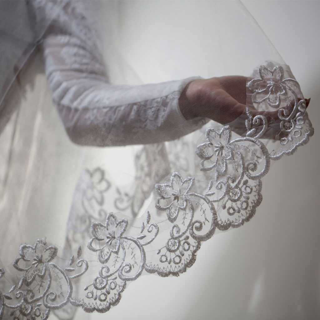 a hand holding a white lace veil