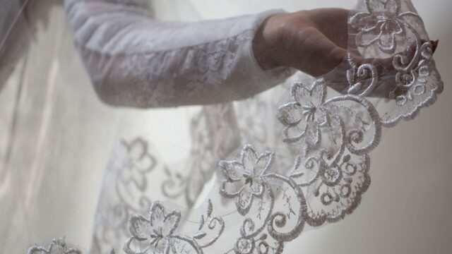 a hand holding a white lace veil