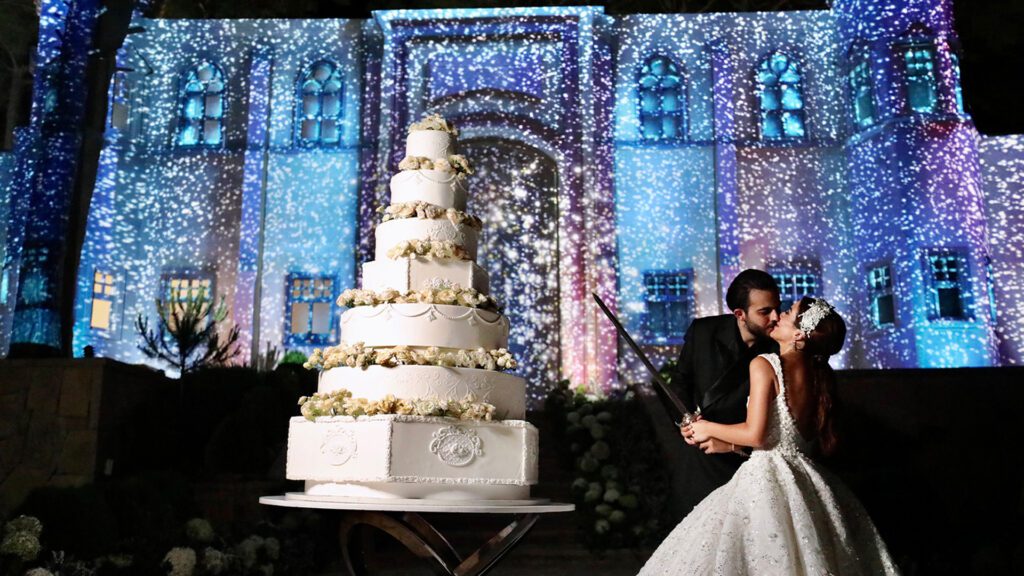 a man and woman kissing in front of a large cake