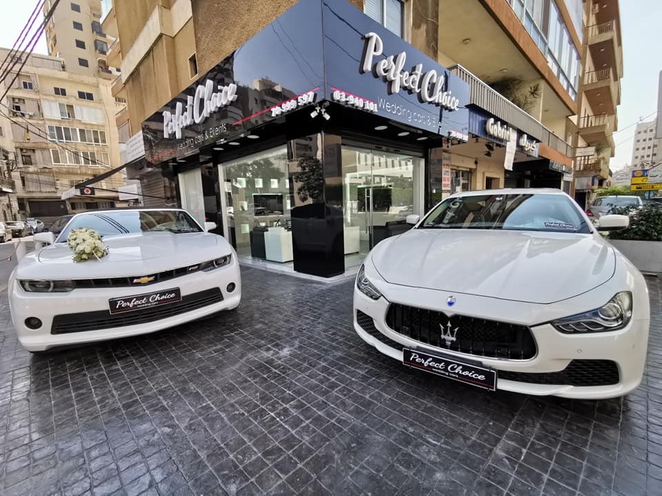 a couple of white cars parked outside a building