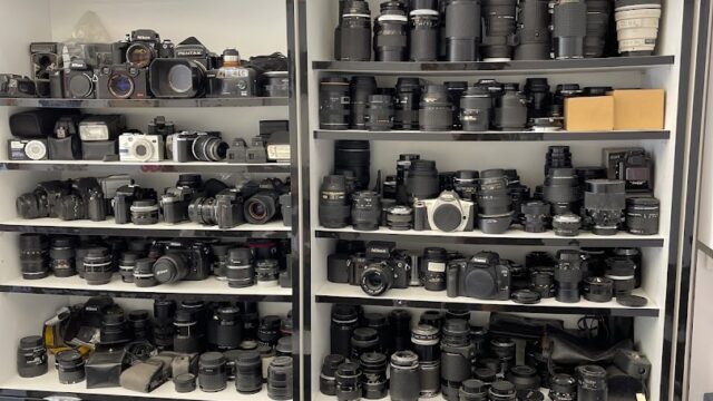 A large collection of Photo Paladium cameras on shelves.