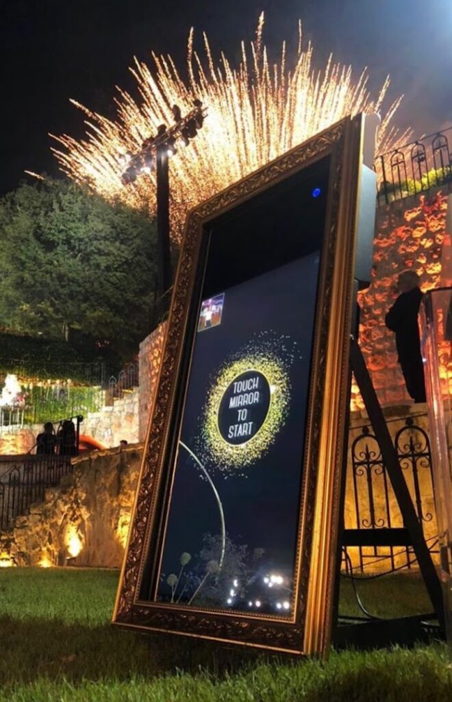 A large mirror with fireworks in the background captures the unforgettable moments at the PicMe Photobooth.