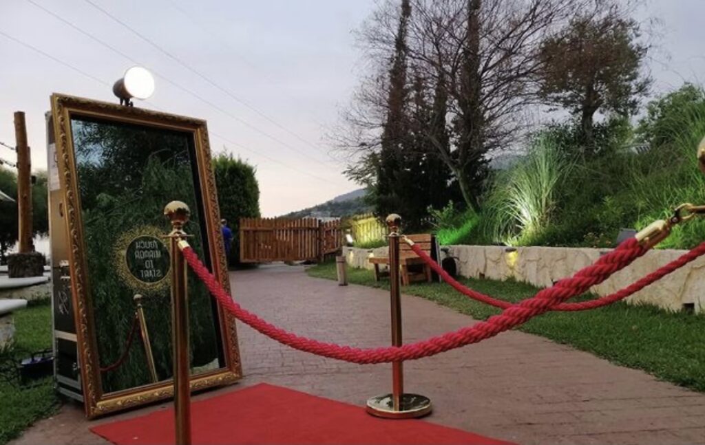 A red carpet with a rope around it leads the way towards the glamorous "PicMe Photobooth".