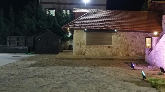 a stone house with a red roof and a stone garage