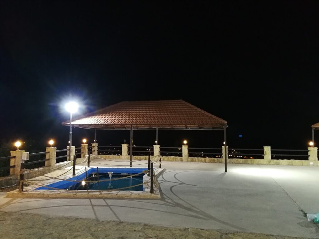 a gazebo with a pool and lights at night