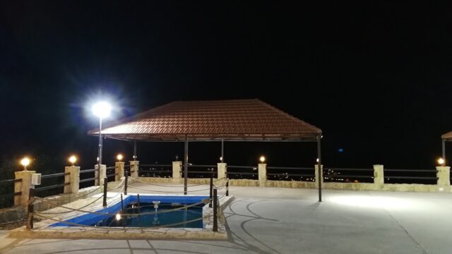 a gazebo with a pool and lights at night