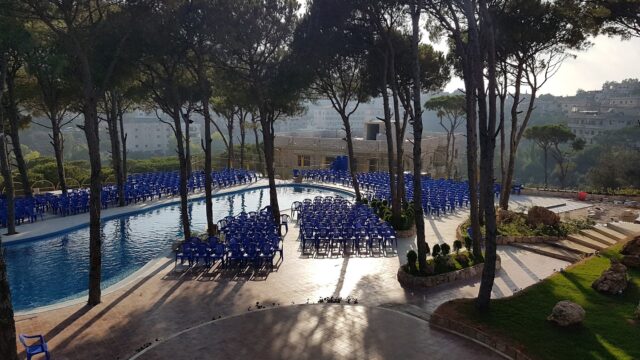 a pool with blue chairs and trees