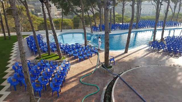 a pool with blue chairs and trees