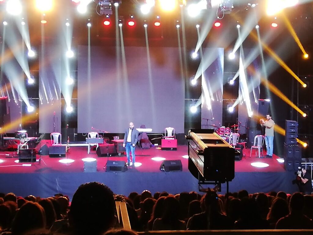 a group of people on a stage with lights and a crowd watching