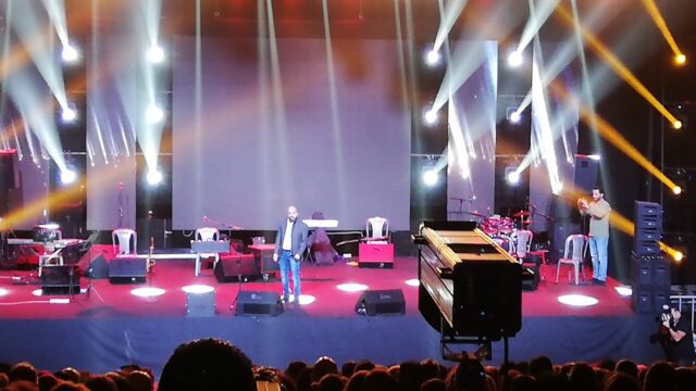 a group of people on a stage with lights and a crowd watching