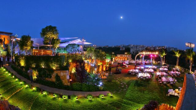 a large lawn with tables and chairs and lights