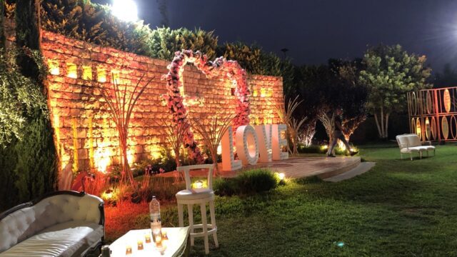 a brick wall with a heart shaped sign and chairs