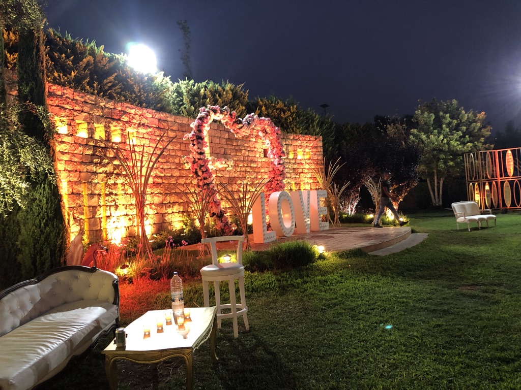 a brick wall with a heart shaped sign and chairs