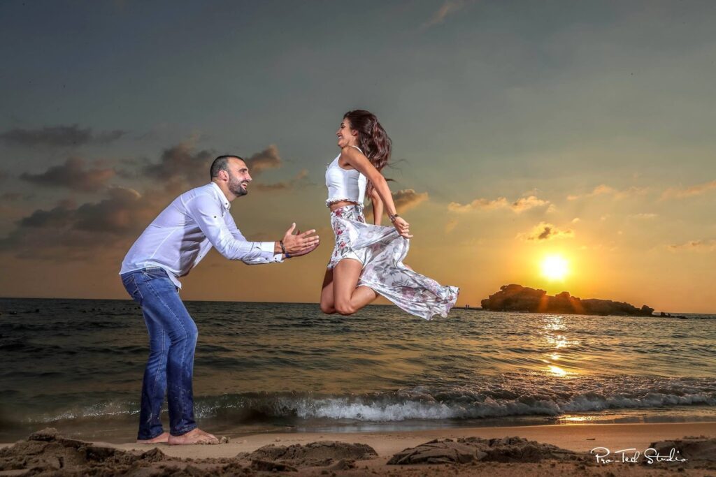 a man and woman jumping in the air on a beach
