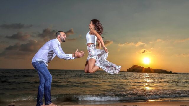 a man and woman jumping in the air on a beach