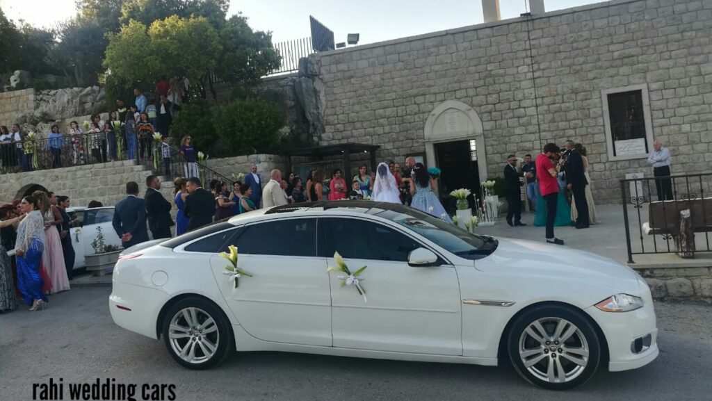 a white car with flowers on the side and people in the background