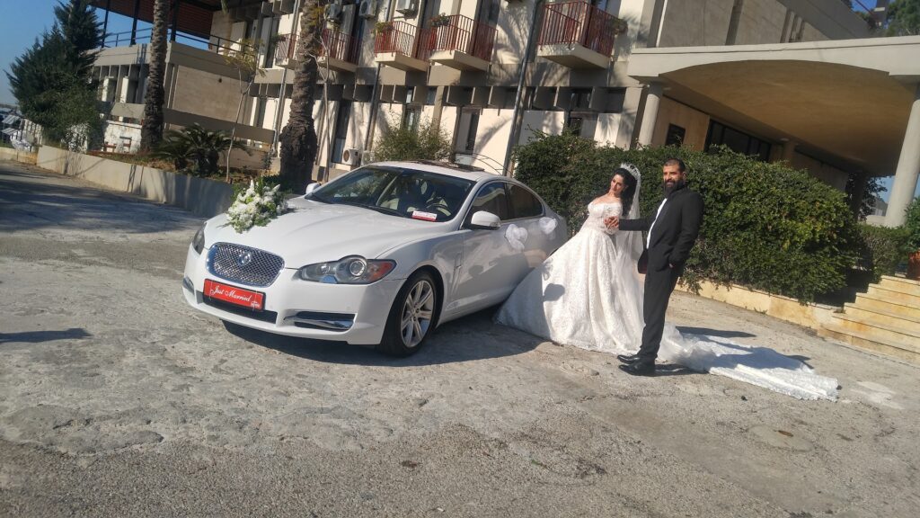 a man and woman in wedding attire standing next to a car