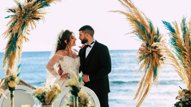 a man and woman kissing under a circular arch with wheat and plants