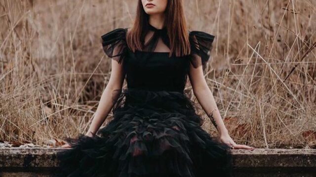 a woman in a black dress sitting on a ledge