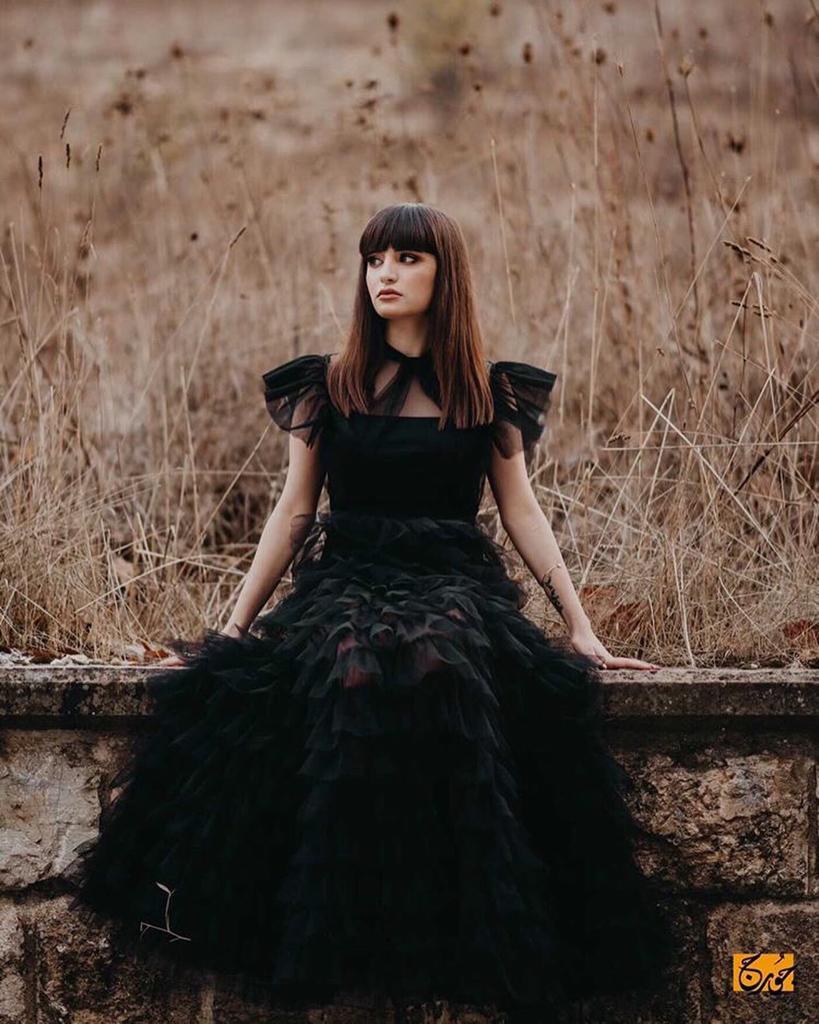 a woman in a black dress sitting on a ledge