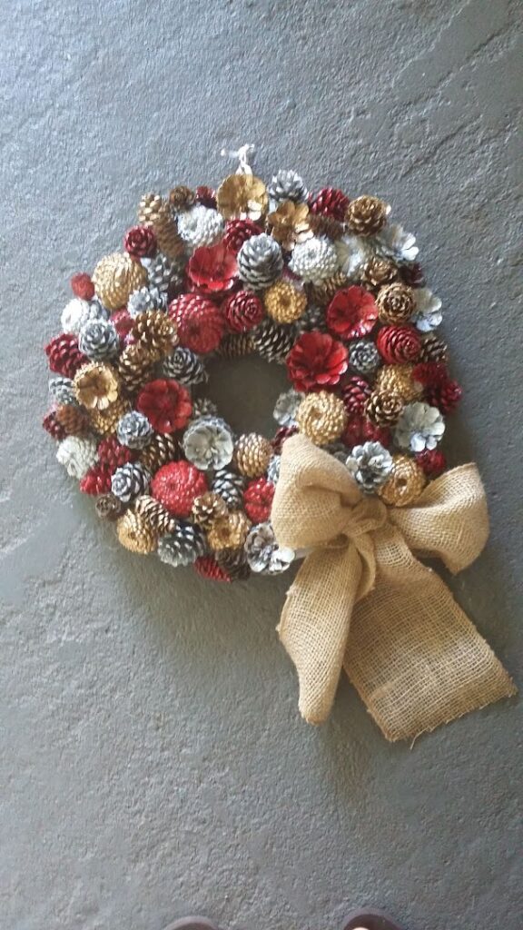 a wreath made of pine cones and a burlap bow