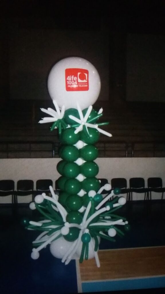 a balloon sculpture with a white ball and green flowers