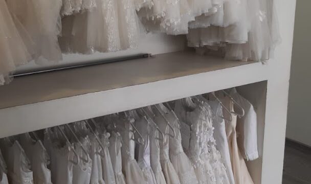 a shelf with white dresses on it