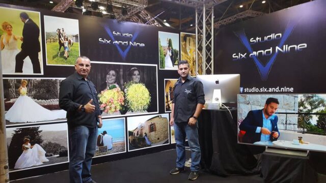 two men standing in front of a wall of photos