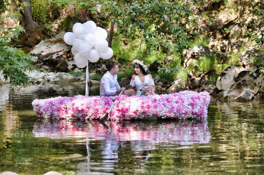 a man and woman in a boat with flowers on the water