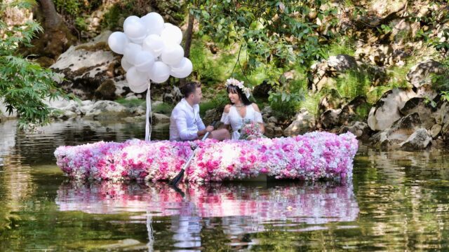 a man and woman in a boat with flowers on the water