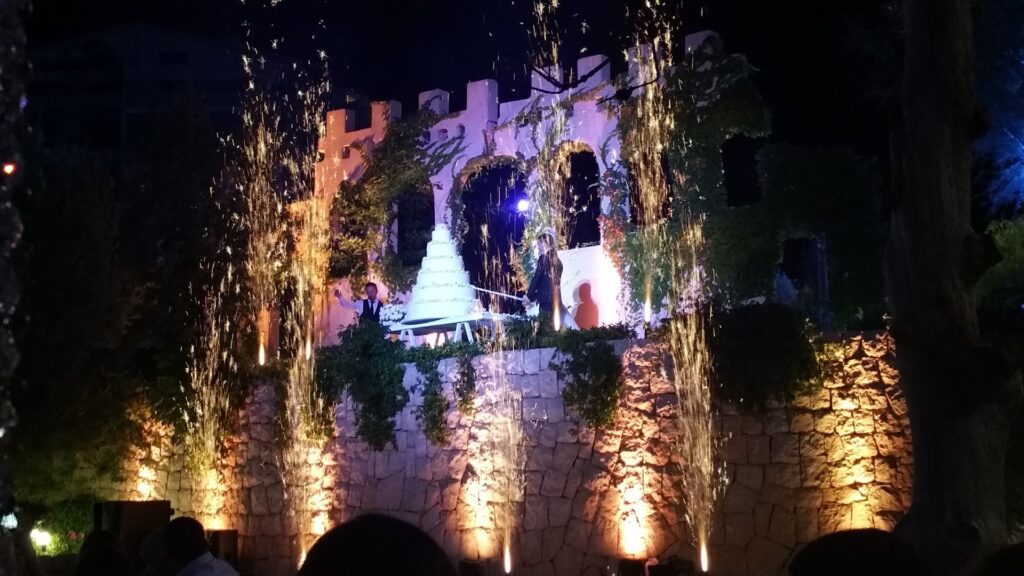 a man standing on a stone wall with a white cake and fireworks