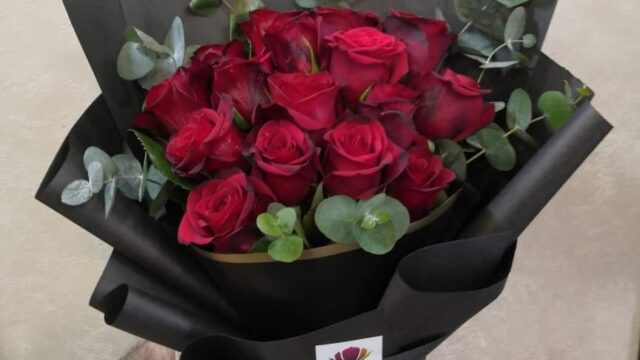 a hand holding a bouquet of red roses