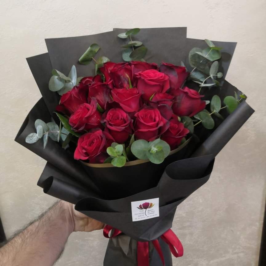 a hand holding a bouquet of red roses