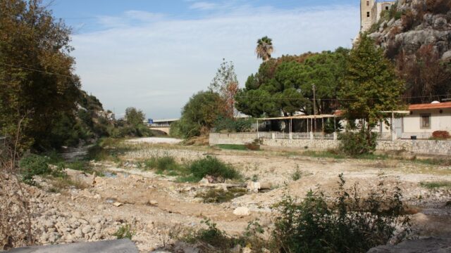 a dirt road with trees and a building in the background