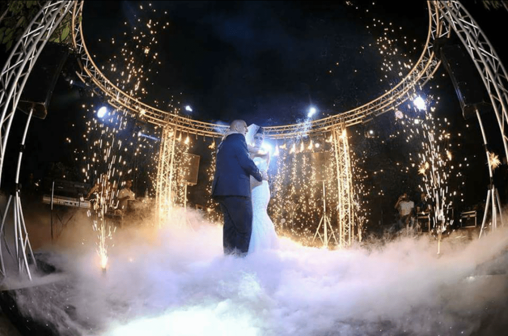 a couple dancing under a stage with fireworks