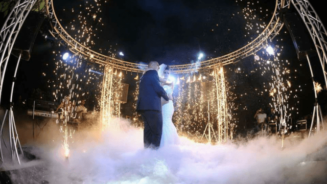 a couple dancing under a stage with fireworks