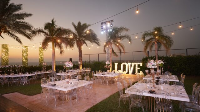 a group of tables and chairs outside with lights and palm trees