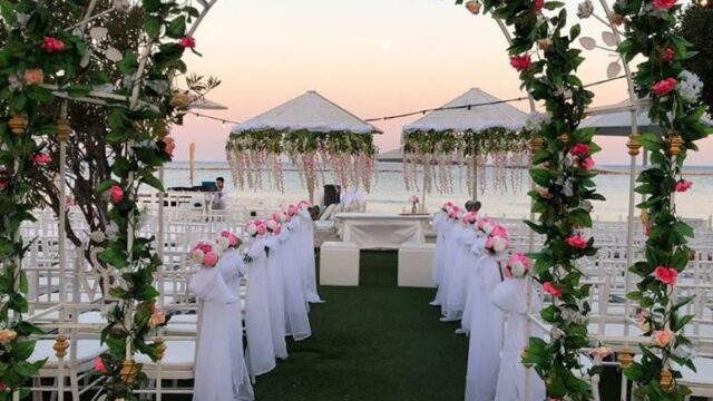 a wedding ceremony with white chairs and flowers